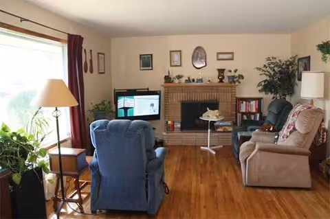 Cozy living room with recliners, sofa, TV, fireplace, and potted plants.
