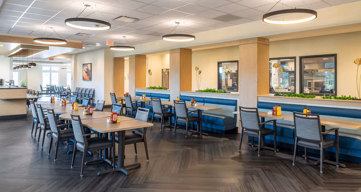 Bright, modern dining room with tables, chairs, blue banquette seating and pendant lights.