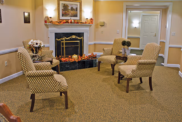 Small sitting room with patterned armchairs arranged around a fireplace decorated with autumn accents.