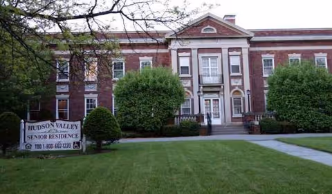 Brick exterior of Hudson Valley Senior Residence with manicured lawn and entrance sign.