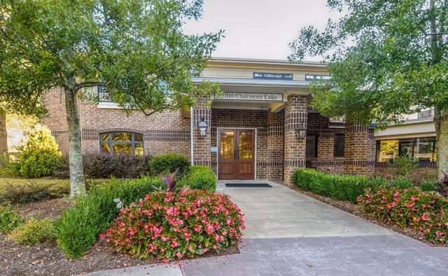 Montclair Assisted Living facility entrance with brick facade, trees, and colorful landscaping.
