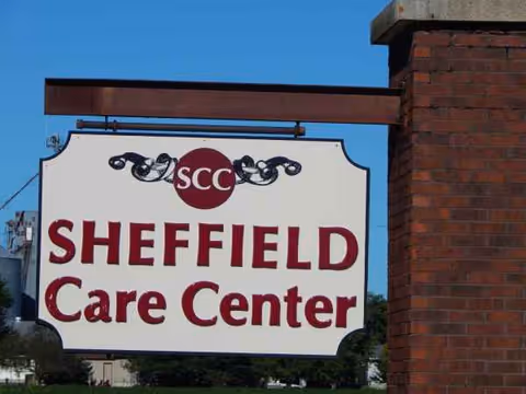 Outdoor sign reads Sheffield Care Center with SCC logo beside a brick pillar.