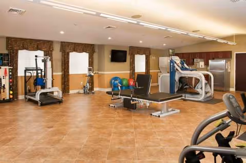 Interior fitness center with treadmills, weight machines, and benches in a rehabilitation facility.