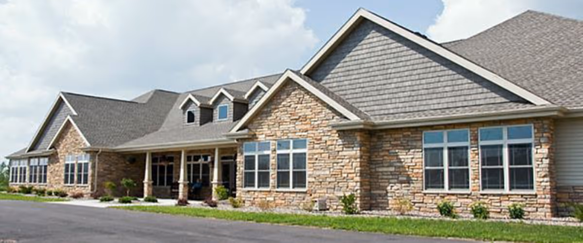 Exterior view of a stone-faced senior living facility with large windows.