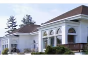 White building with arched windows and a small outdoor seating area at the front.