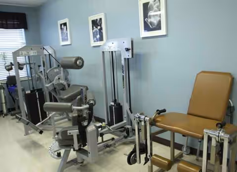 Interior gym area with weight machines and a brown padded chair in a care center.