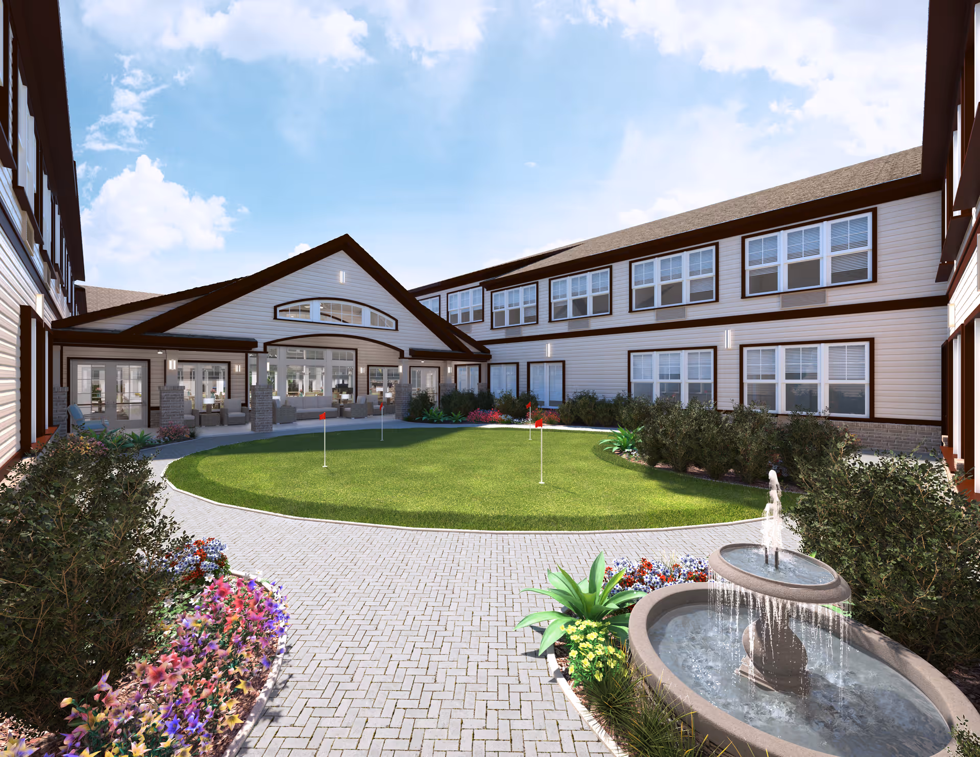 Outdoor courtyard area of a senior living facility with a putting green, surrounded by a paved walkway, flower beds, shrubs, and a two-story building with many windows. There is a water fountain in the foreground and seating areas near the building entrance under a covered patio.