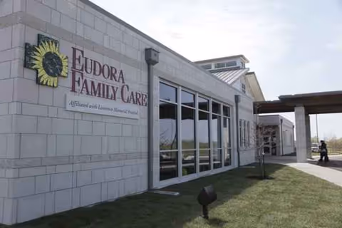 Exterior view of a light brick building with 'Eudora Family Care' signage and glass entrance.