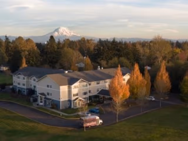 Exterior view of King's Manor Senior Living Community with surrounding trees and distant mountains.