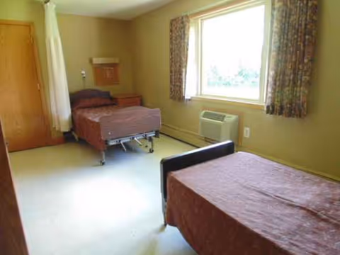 Two beds in a small shared nursing room with a window.