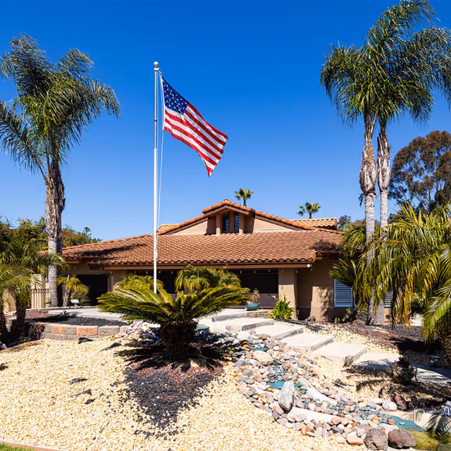 Exterior view of Canyon Villas Retirement Community featuring palm trees and an American flag.