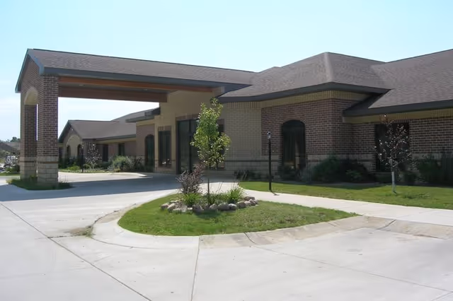 Brick senior living facility exterior with a covered entrance and landscaped circular driveway.