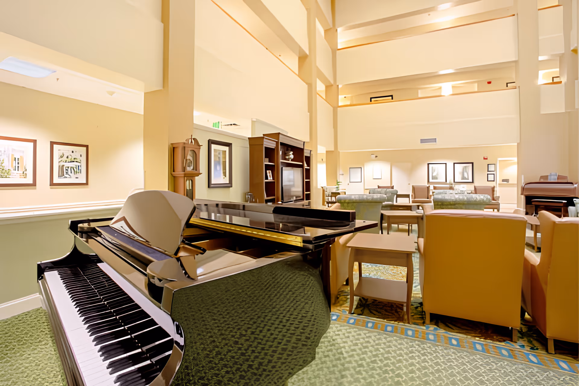 Atrium-style lounge with a grand piano in the foreground and seating areas in a multi-story interior.