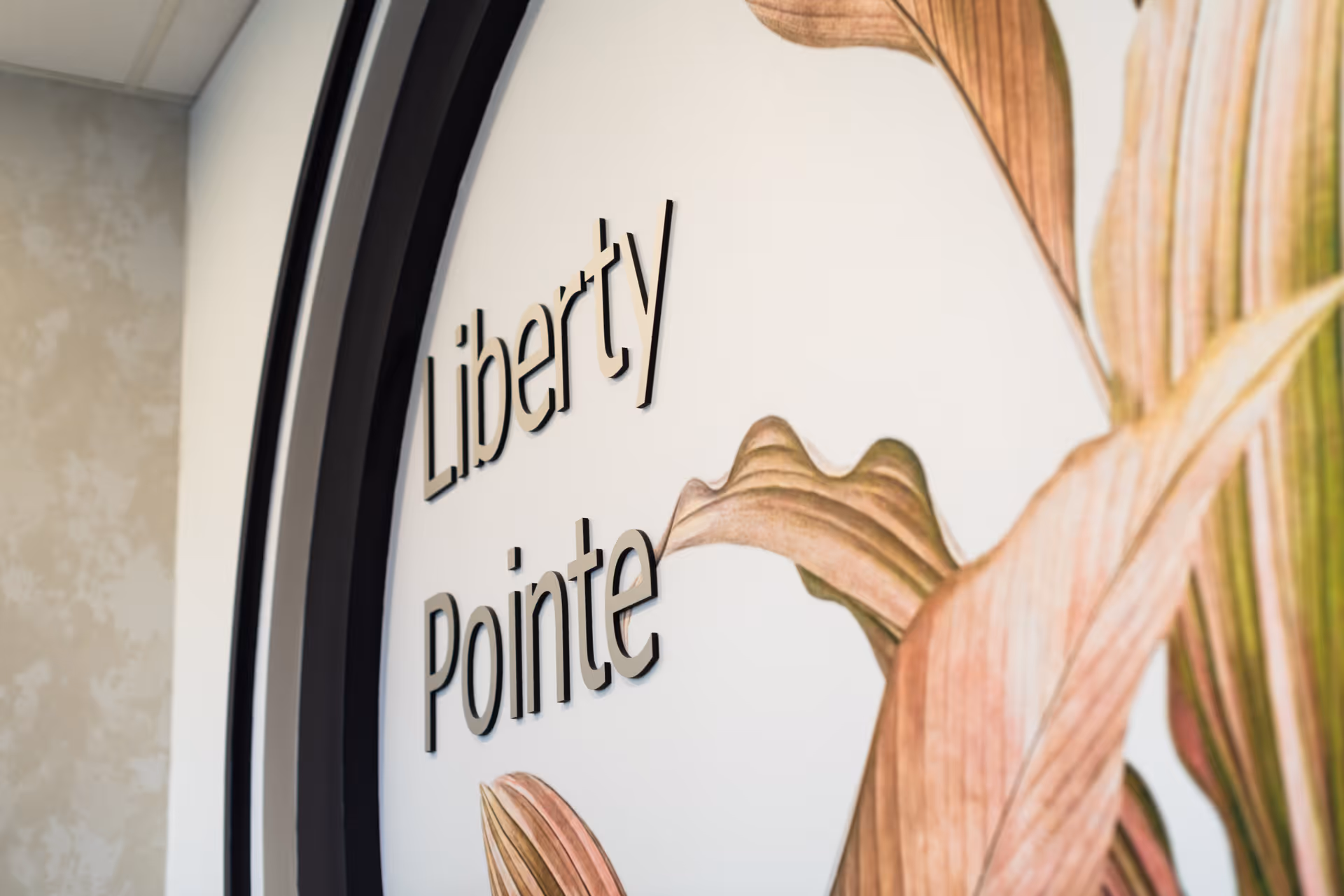 Interior wall sign reading "Liberty Pointe" beside large decorative floral artwork.