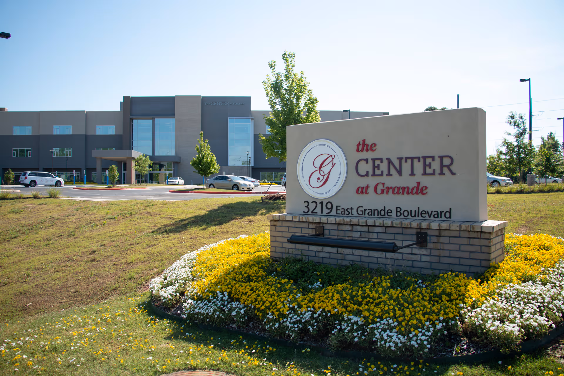 Entrance sign for The Center at Grande with a flowerbed in front and the facility building in the background.