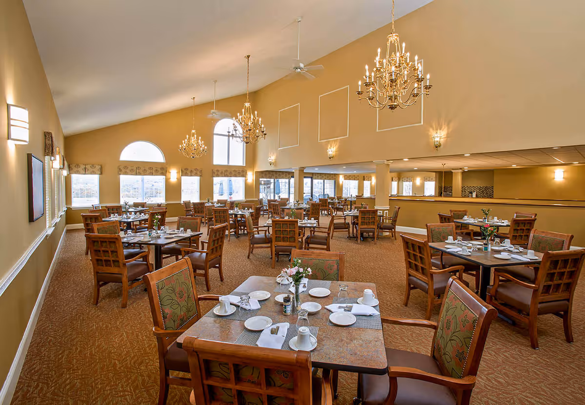 Large, elegant dining room with multiple set tables, chandeliers, and large windows.