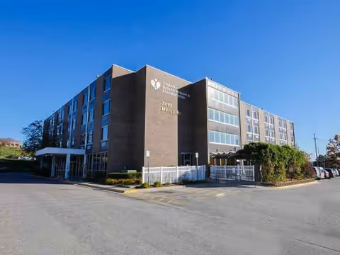 Exterior view of Emerald Nursing and Rehab Mercy facility, brick building with entrance and parking.