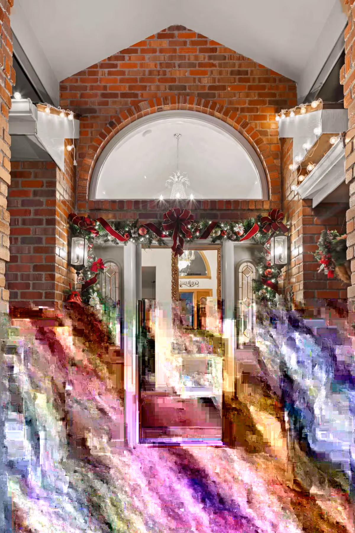 A brick building entrance decorated with holiday garlands and lights, visible through an open doorway.