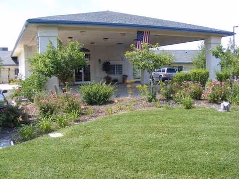 Front view of Arbors Memory Care facility with landscaped entrance and American flag.
