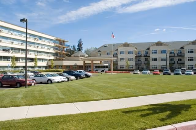 Exterior view of Friendsview Retirement Community showing the building, lawn, and parked cars.