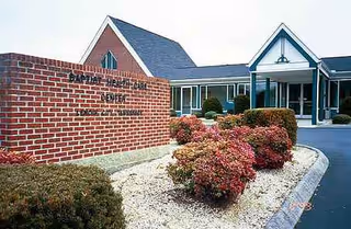 Exterior view of Baptist Health Care Center entrance with landscaped shrubs and brick sign.
