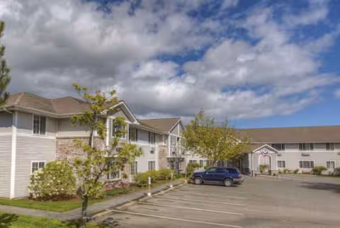 Exterior view of Trustwell Living at Sinclair Place with parked cars and landscaped entrance.