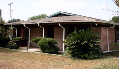 Single-story brick facility with green trim and shrubs along the front entrance.