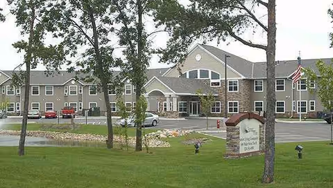 Exterior view of Fairway Pines Senior Living building with manicured lawn and flag