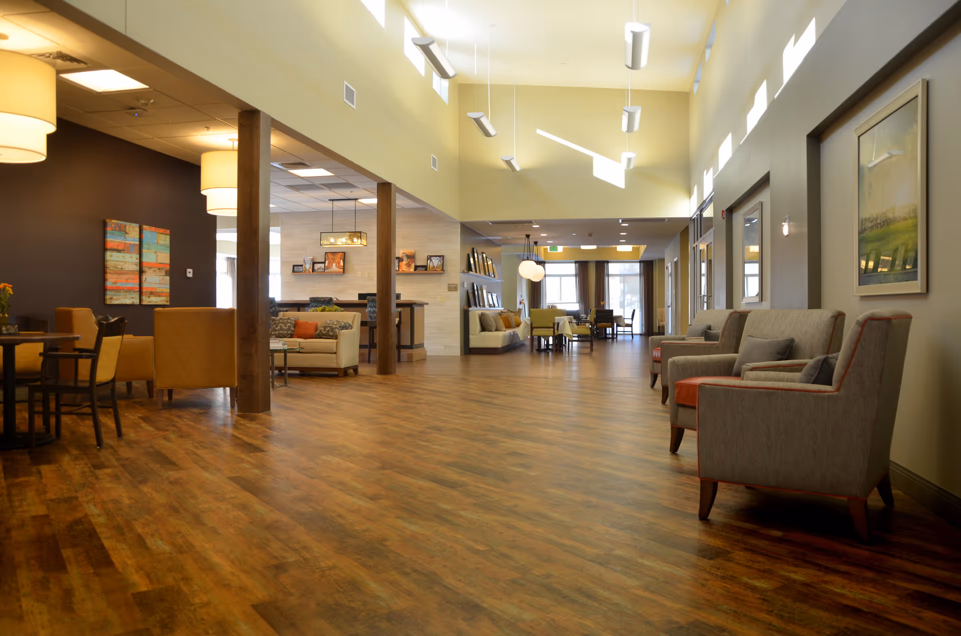 Spacious, well-lit common lounge with high ceilings, wood floors, and multiple seating areas.