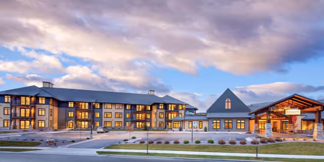 Exterior front view of the Immanuel Living senior facility at dusk showing a multi-story building with lit windows and a covered entrance.