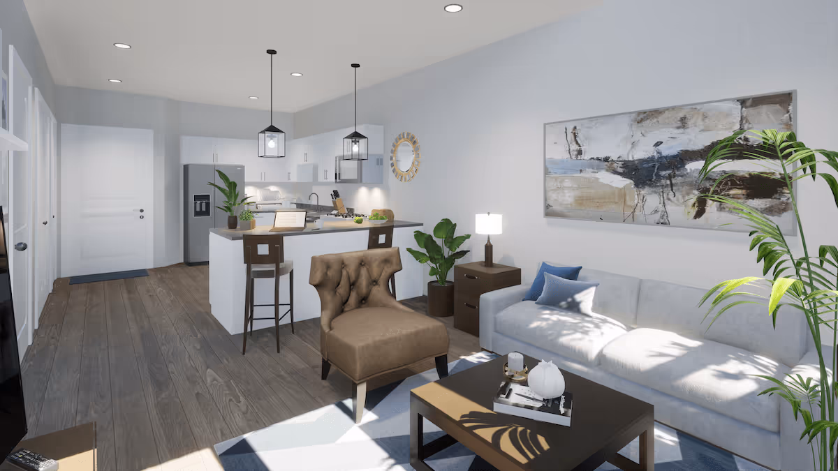 A modern senior living interior featuring an open floor plan with a kitchen and living room. The kitchen has white cabinets, a refrigerator, and a countertop with two bar stools. The living room includes a white sofa with blue pillows, a brown armchair, a coffee table with decorative items, a side table with a lamp, and green plants. A large abstract painting hangs on the wall, and the space is well-lit with natural light and ceiling lights.