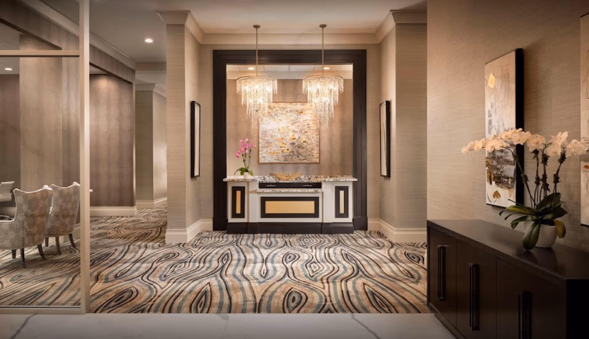 An elegant interior lobby area featuring a decorative counter, artwork, and modern lighting.