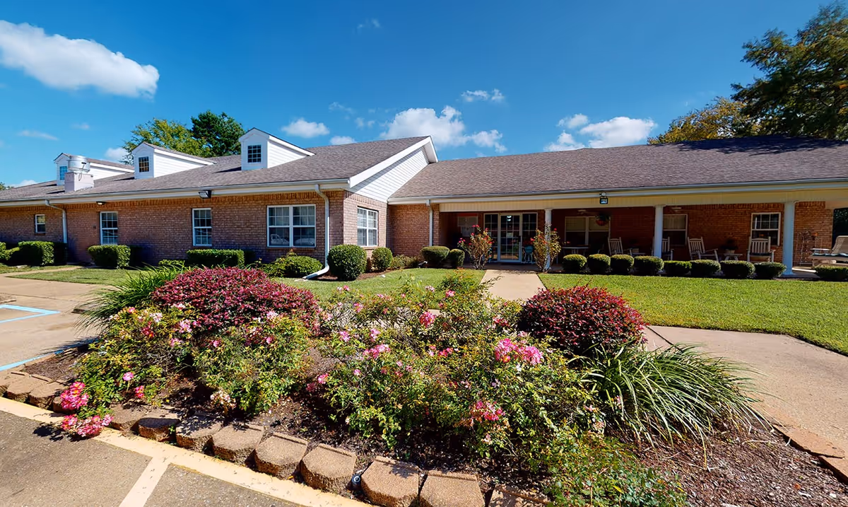 Exterior view of Azalea Place building with a landscaped front garden and porch seating.