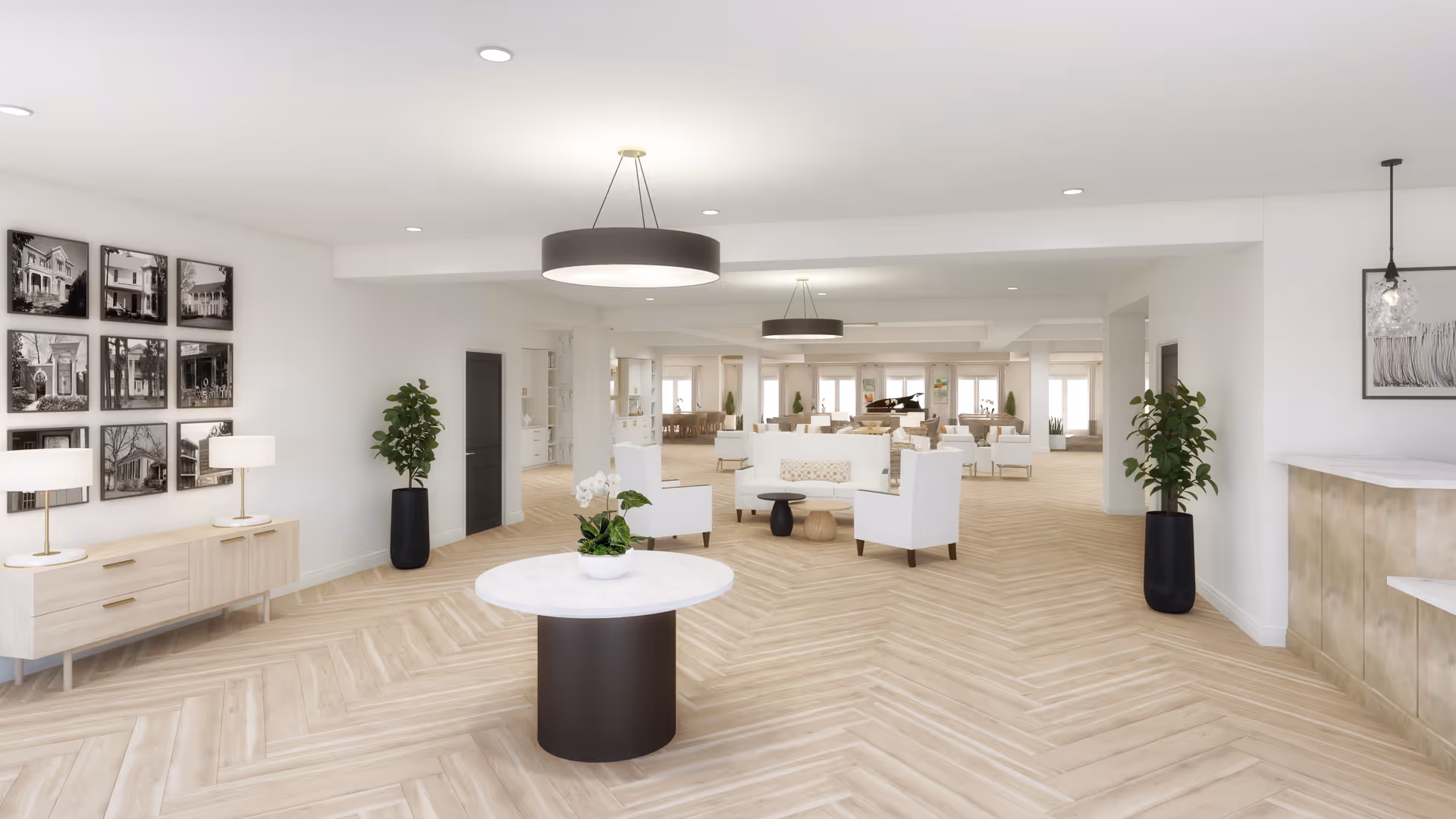 Bright modern communal lounge with light herringbone wood floors, white seating, a round marble-top center table with a plant, and pendant lights.