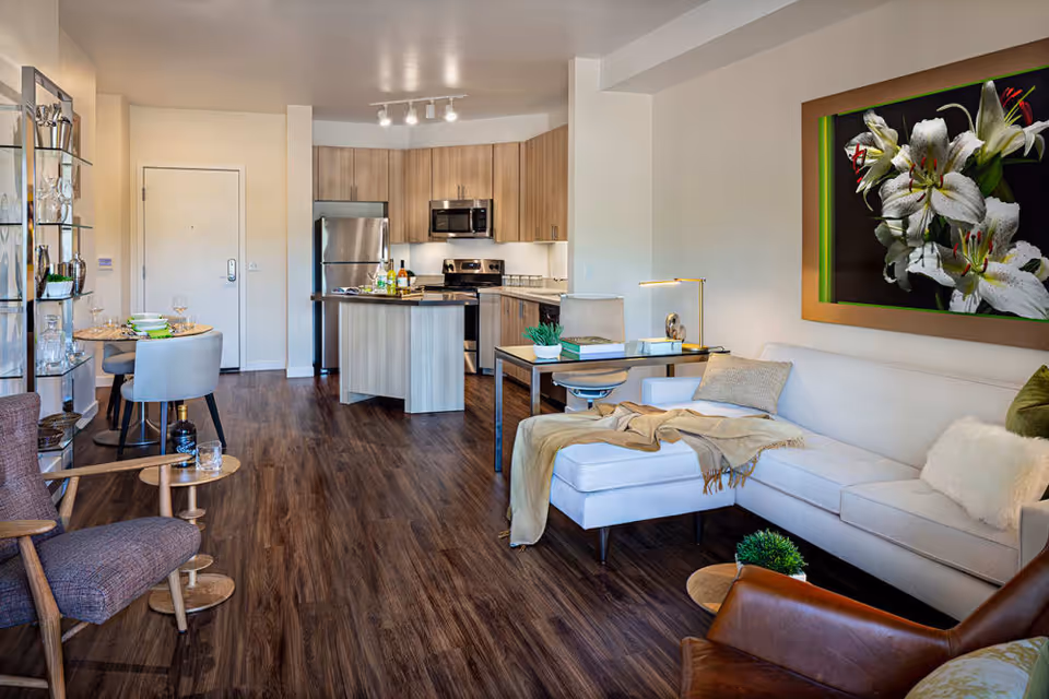 Open-plan living area with a sectional sofa, armchairs, dining nook, and a kitchen with an island.