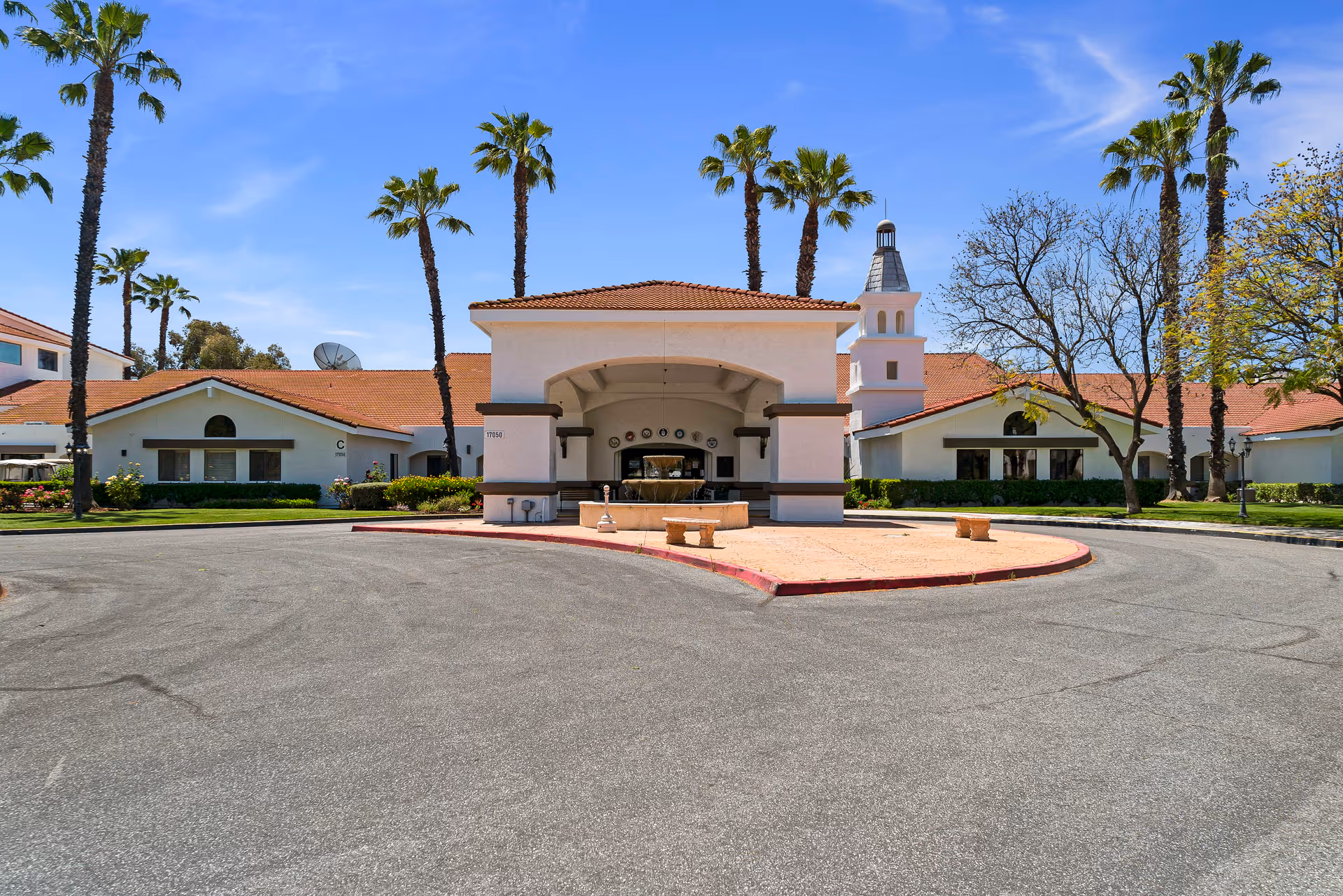 Front exterior view of Westmont of Riverside facility showing a circular driveway with a covered entrance, palm trees, and a clear blue sky.