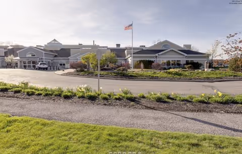 Exterior view of Dosberg Manor Adlt Hme-Menorah with landscaped entrance and flagpole.