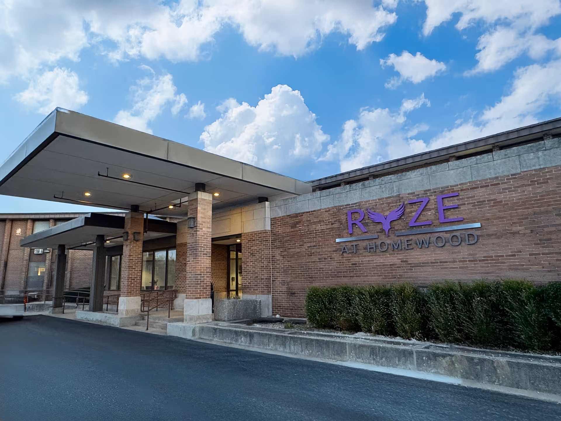 Exterior view of RYZE at Homewood senior living facility showing entrance and signage.
