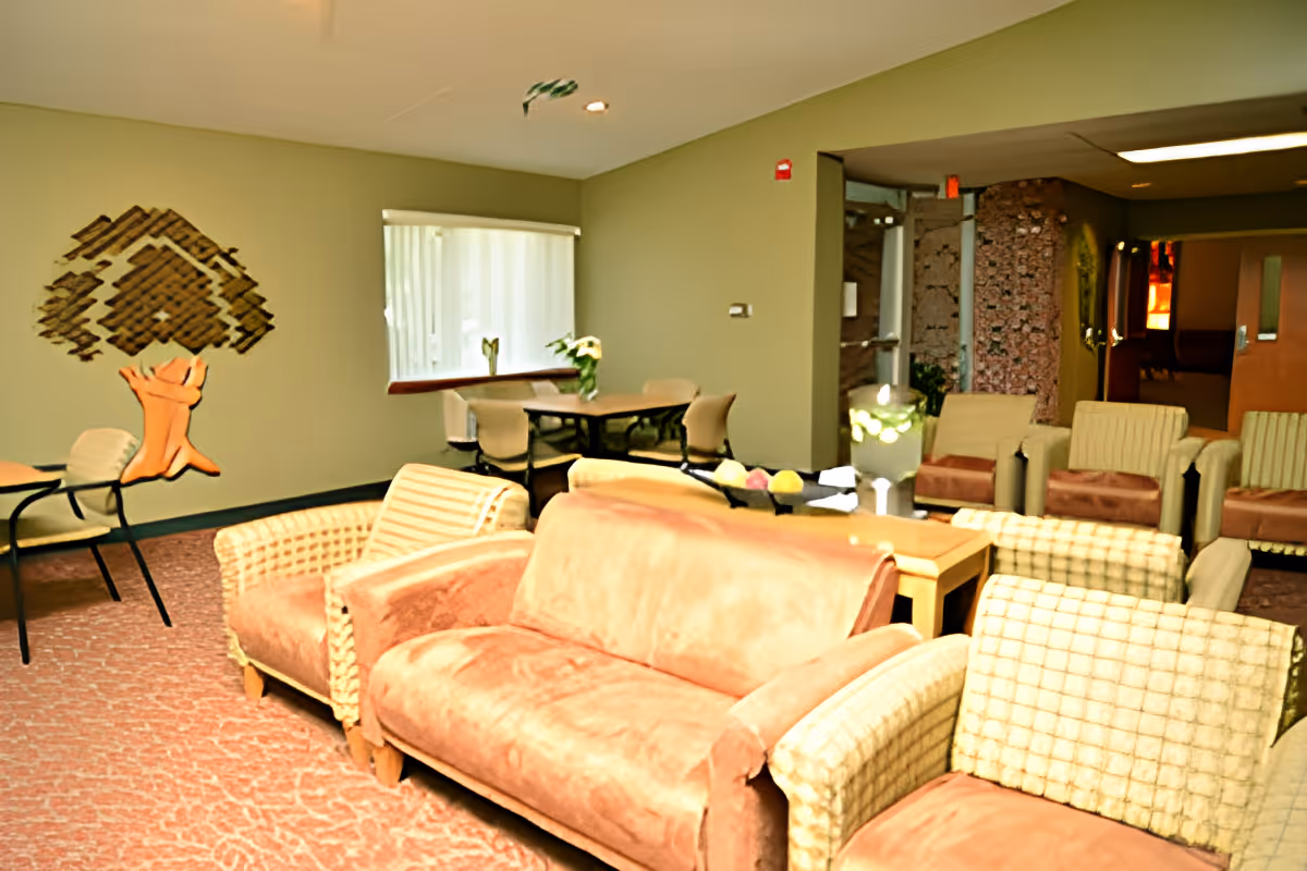 A comfortable communal lounge with sofas, armchairs, tables, and wall art.