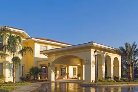 The Windsor of Venice: yellow building with arches, palm trees, and a covered entrance.