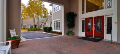 Exterior view of Regency House of Buford entrance with red doors and brick-paved walkway.