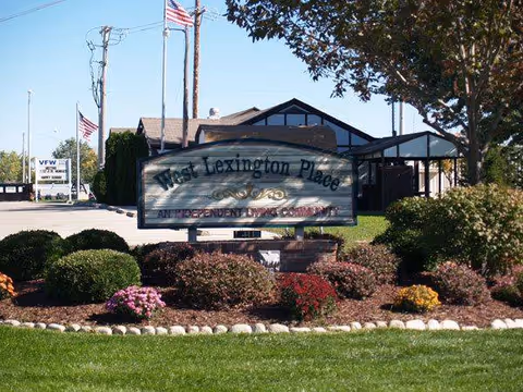 Front exterior view of West Lexington Place with landscaped sign and building in background