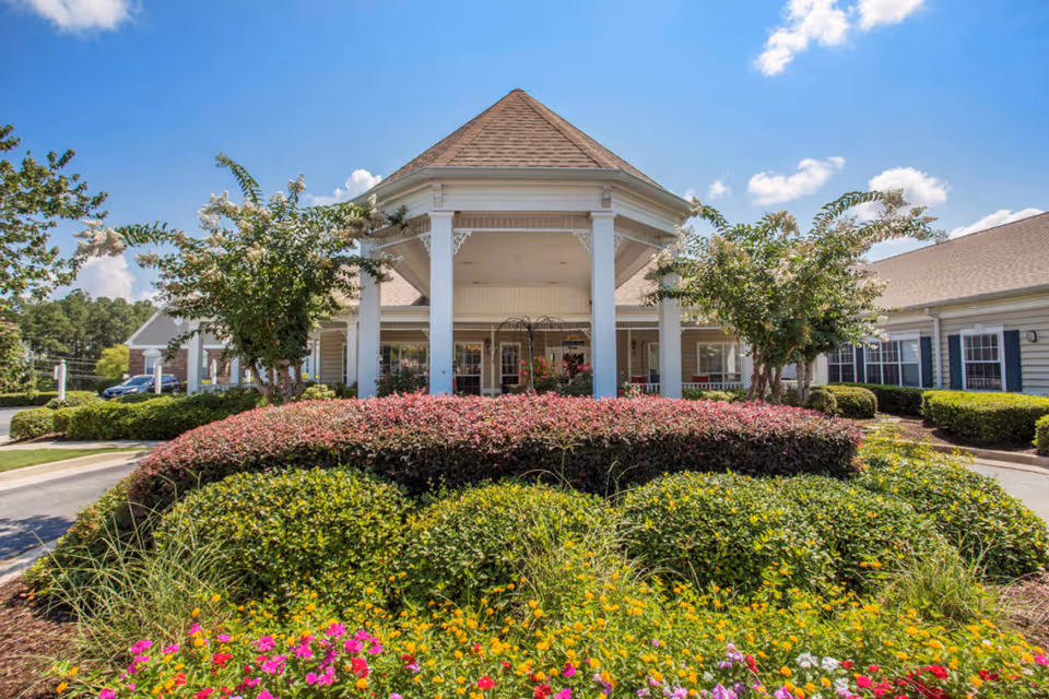 Front entrance of Oaks at Evans with a covered porch and colorful flower beds.