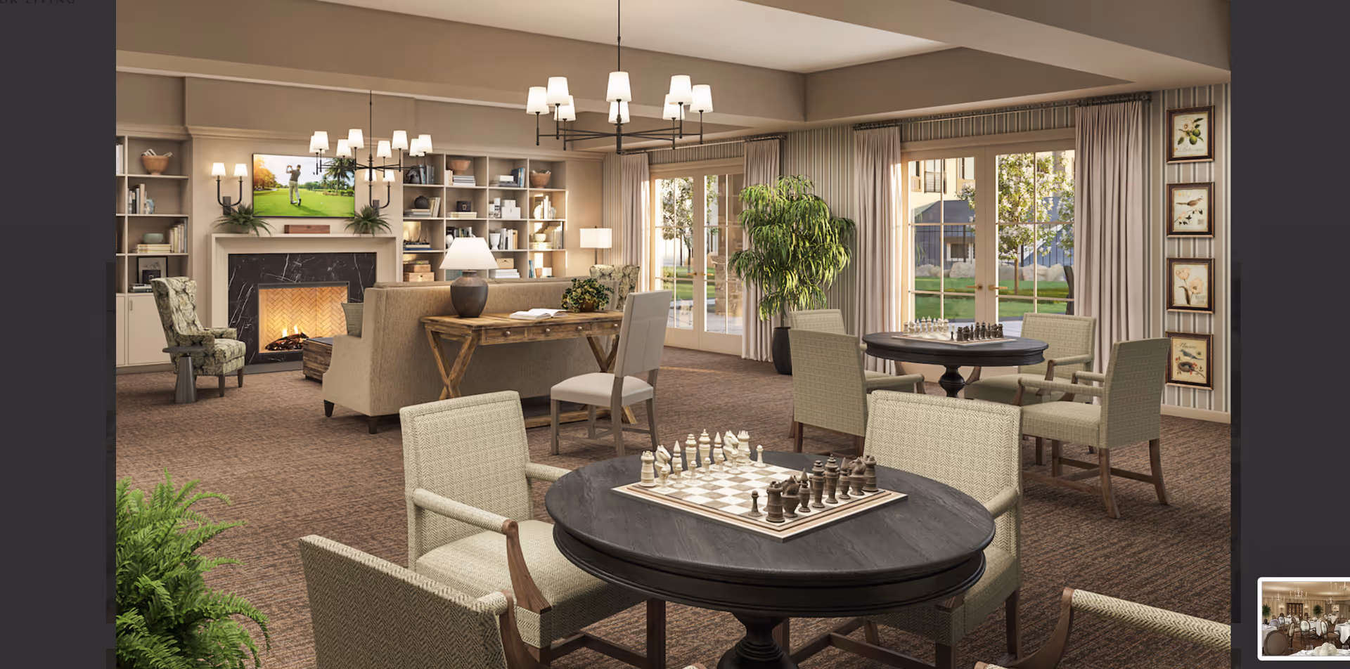 A spacious senior living common area with multiple round tables set up for chess games. The room features comfortable upholstered chairs, a fireplace with a TV mounted above it, built-in bookshelves, large windows with curtains letting in natural light, and decorative plants. The decor is warm and inviting with neutral tones and soft lighting.