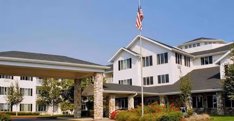 Exterior view of Solista Newberg facility with flagpole, covered entrance, and landscaped grounds.