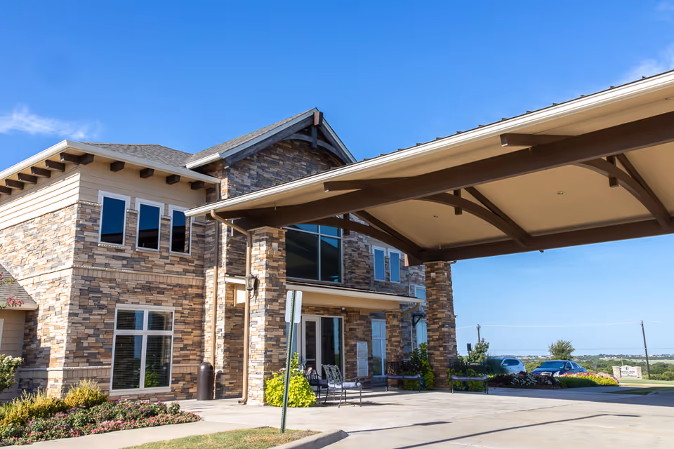 Stone-clad senior living facility exterior with a covered entrance and blue sky
