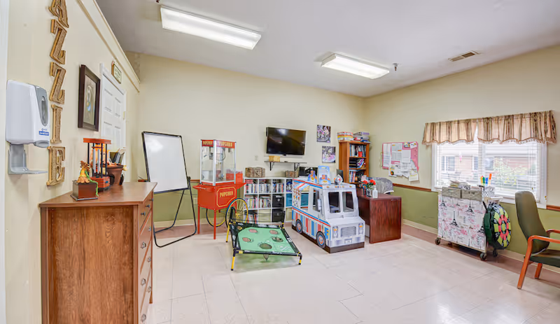 Activity room with a toy ice cream truck, popcorn cart, TV, bookshelves, and seating.