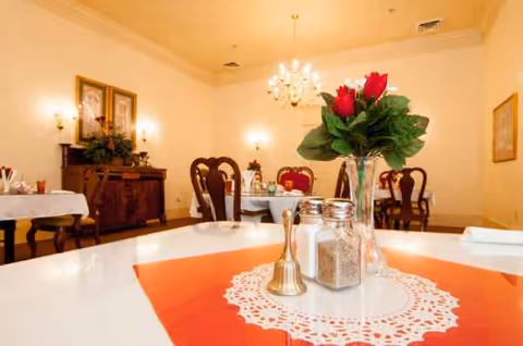 Dining room at Magnolia Estates of Oconee with tables, chairs, and floral centerpiece.