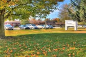 View of the exterior grounds of Valley View Healthcare Center with a grassy lawn, trees with autumn leaves, several parked cars, and a sign displaying the facility's name.