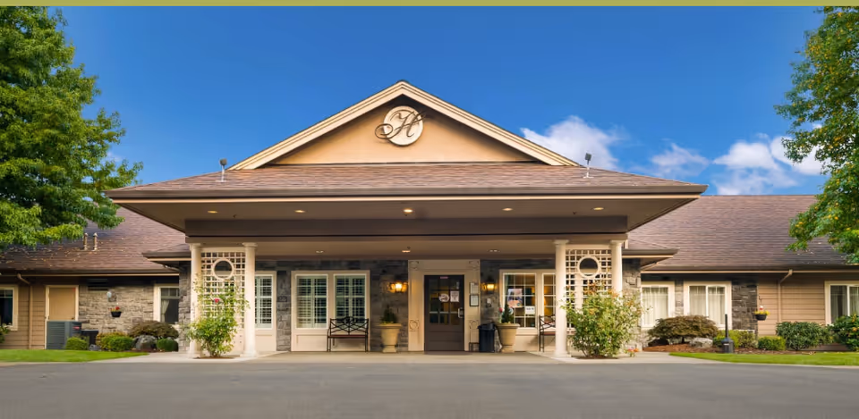 The Hampton senior living facility entrance with columns and a gabled roof.